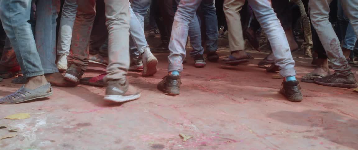 A crowd of peoples feet are bumping into each other and walking into one another as another person walks past