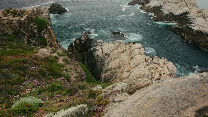 An aerial view of waves rolling in towards cliffs on the bank