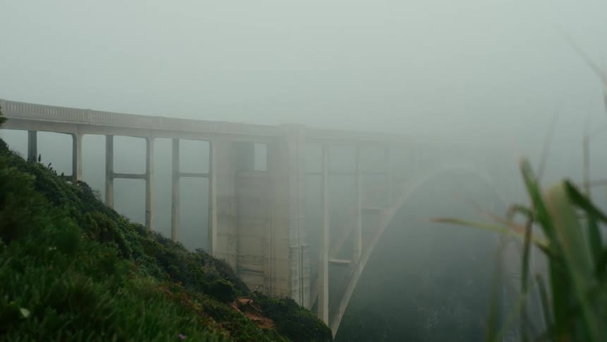 An arched bridge with one end covered by fog