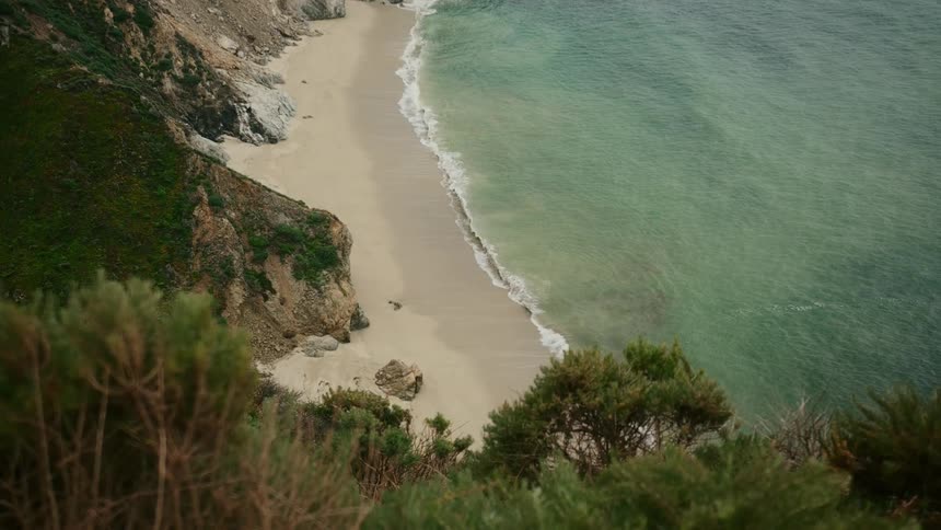 A beach in a small bay seen from over a cliff