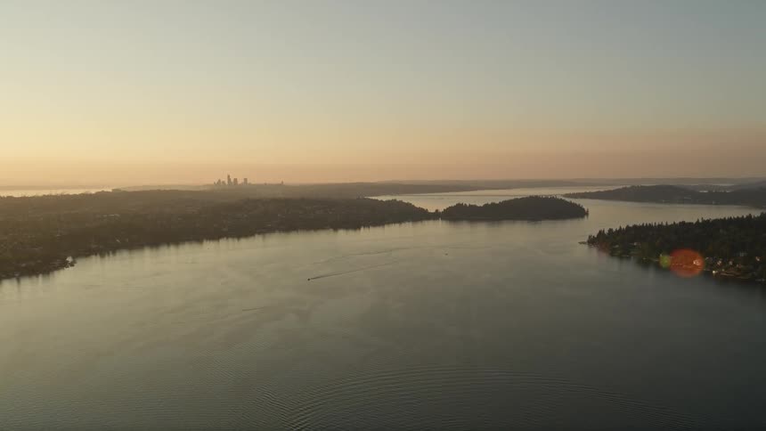 A stunning aerial view of the distant Downtown Seattle skyline at sunset as seen while flying over Lake Washington