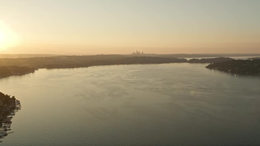 anaerial footage capturing the stunning sunset over Lake Washington and the majestic Downtown Seattle skyline as the drone approaches showcasing the clear skies and natural beauty of Washington State