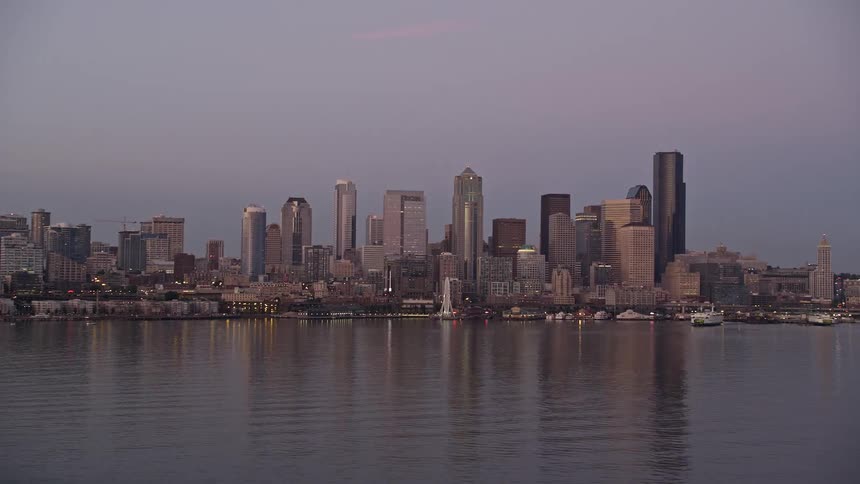 Aerial view of Downtown Seattle skyline and Central Waterfront at sunset with high-rise buildings and boats docked on the shoreline