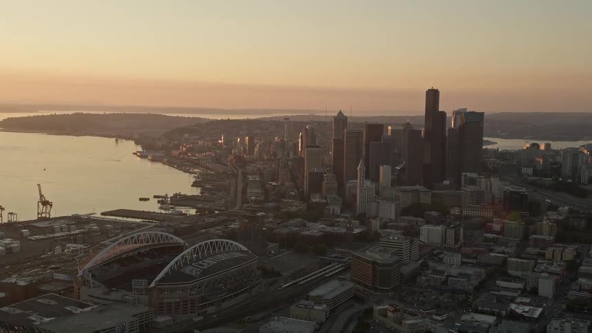 Aerial footage of Downtown Seattle at sunset showcasing high-rise buildings Safeco Field port cargo cranes and the city's vibrant waterfront industrial scene