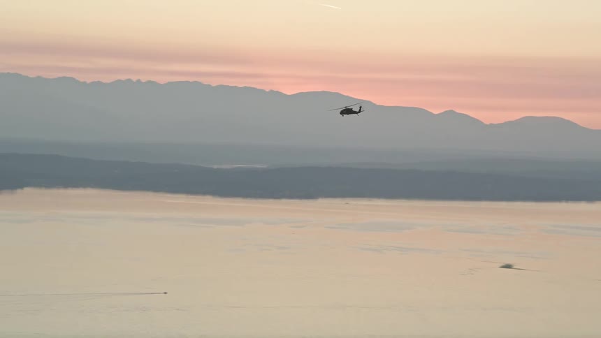 A military helicopter tracks over Puget Sound at sunset in Washington State