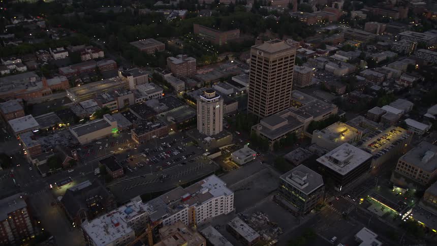 Aerial view of office buildings in University District Seattle tilting up to reveal the bridge and Lake Union during twilight