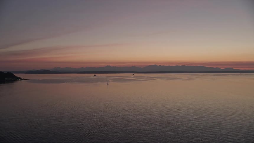 Stunning aerial view of Puget Sound at dusk with mesmerizing sunset colors dancing across the partly cloudy skies in Seattle Washington