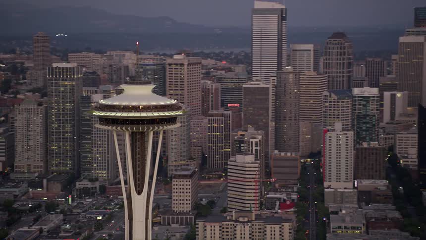an aerial view of the iconic Space Needle surrounded by the cityscape of Downtown Seattle during sunset