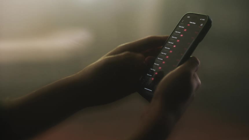 Two hands hold a smartphone and scroll through an app
