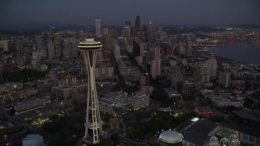  aerial footage capturing the breathtaking sight of Downtown Seattle's towering skyscrapers as seen from a flying perspective near the iconic Space Needle during twilight