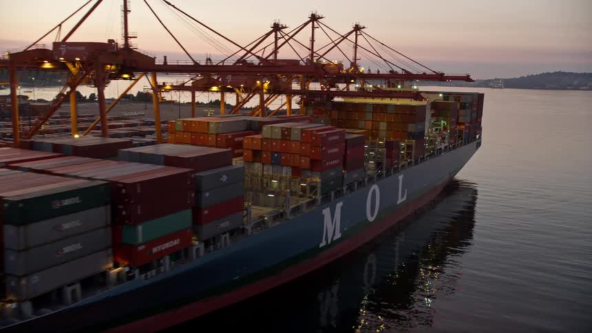 Aerial view of loaded cargo ships docked beneath cranes at the Port of Seattle Washington during sunset