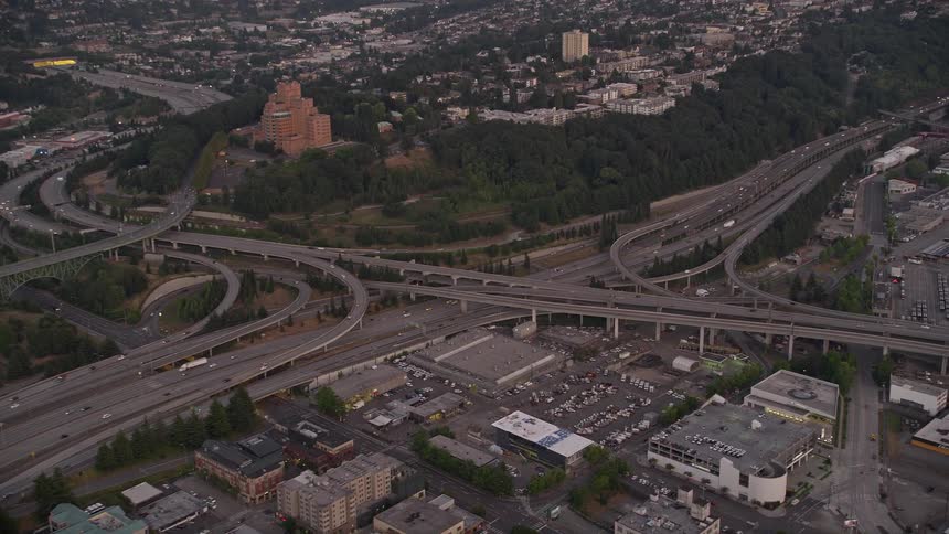 Aerial footage of the I-5 / I-90 interchange in Beacon Hill Seattle Washington during sunset showcasing the clear skies and light traffic in the bustling city