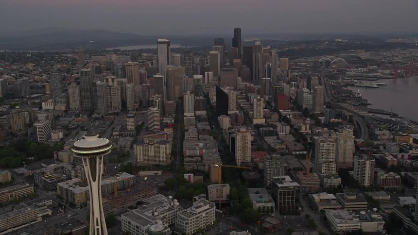 Aerial footage captures the iconic Space Needle and downtown skyscrapers as the camera orbits and tilts to reveal the cityscape during a beautiful sunset in Seattle Washington