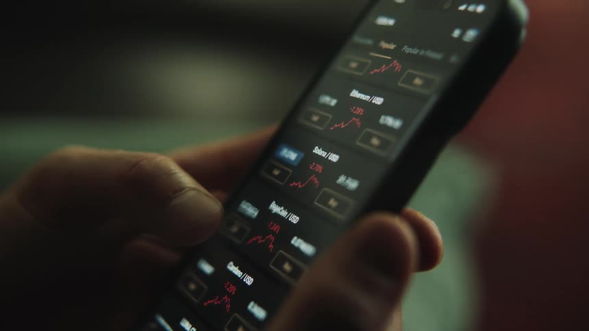 A close up of a person scrolling on their cellphone looking at numbers and graphs