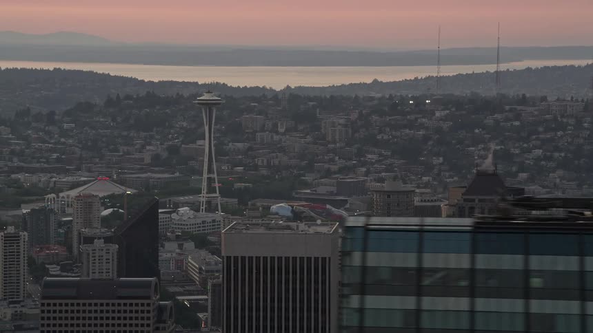 An aerial view of the iconic Seattle Space Needle and downtown skyscrapers during sunset in vibrant and hazy Seattle Washington