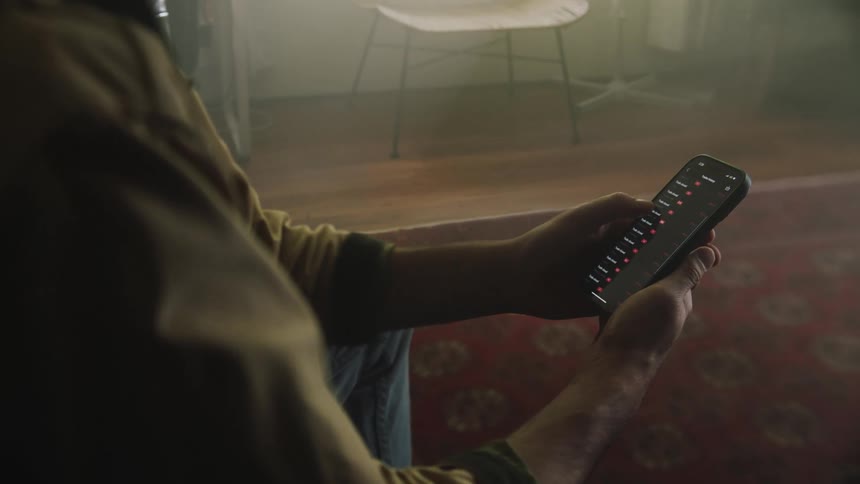 A close up of a man sitting while using his cellphone scrolling on the screen