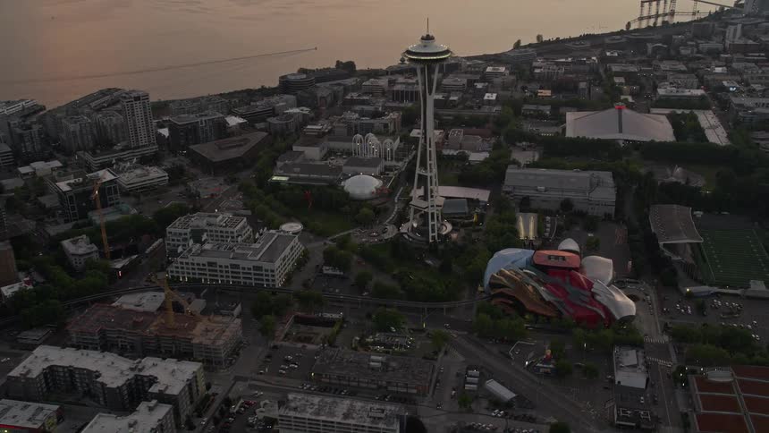 Aerial footage of Downtown Seattle skyscrapers and the Space Needle at sunset with a tilt revealing the city's famous landmarks and skyline