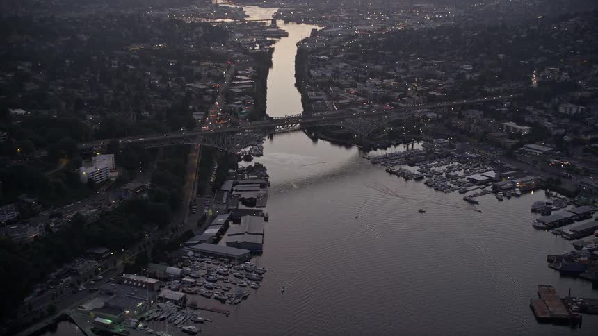 Aerial footage of the Aurora Bridge crossing over the Fremont Cut at sunset with cloudy skies and scenic views of Lake Union in Seattle Washington