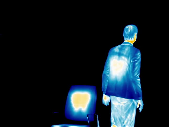 A man filmed in infrared gets up and waves
