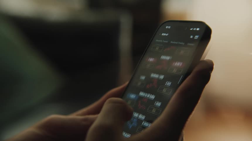 A man scrolls through stock results on his phone