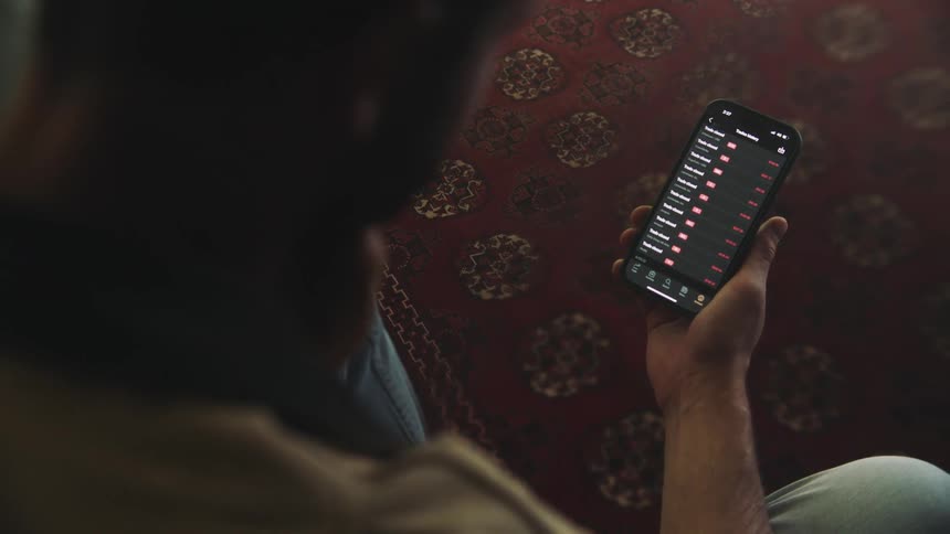An up close of a man sitting using his cellphone scrolling on the screen