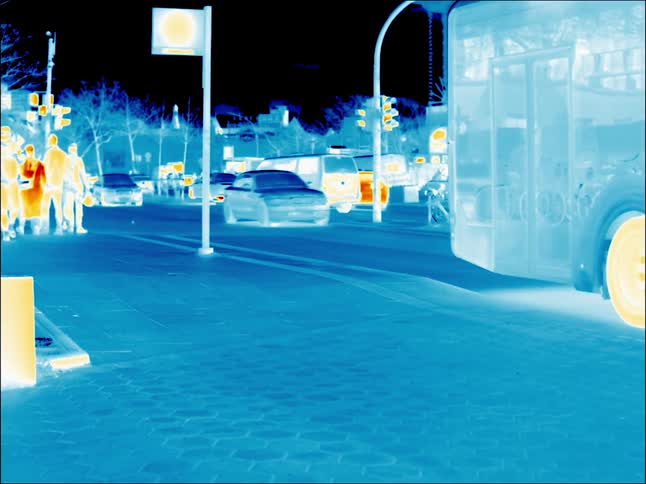 An infrared view of people and cars outdoors