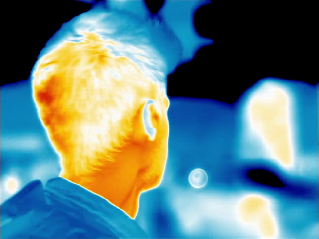 A man is standing outside on a city street in infrared
