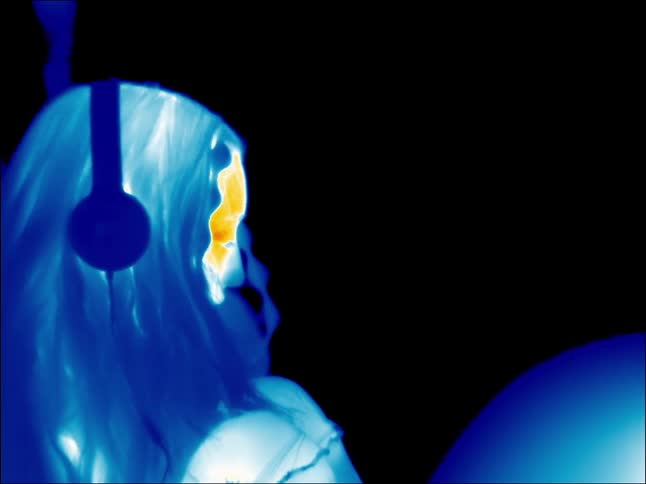 Woman wearing headphones bobs her head in infrared image
