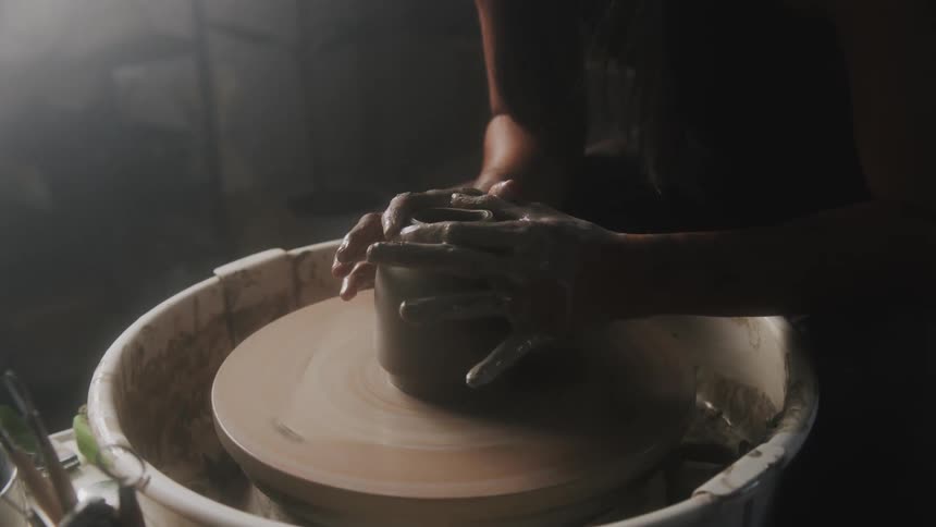 A woman is playing with clay doing pottery indoors