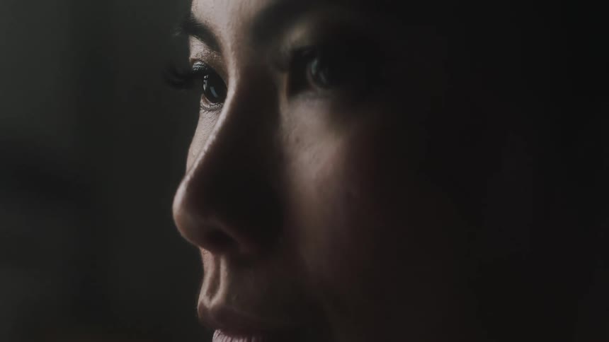 An up close portrait of a womans face as she blinks and looks down