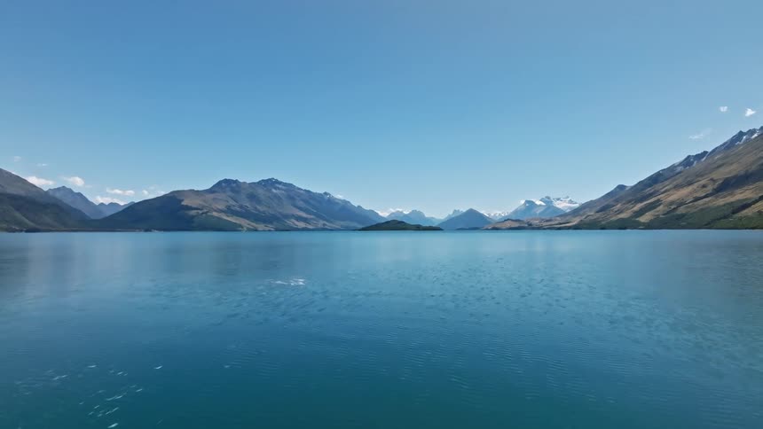 A distant mountain range flying over a calm body of water