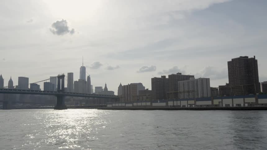 Traveling on a body of water toward a bridge and city