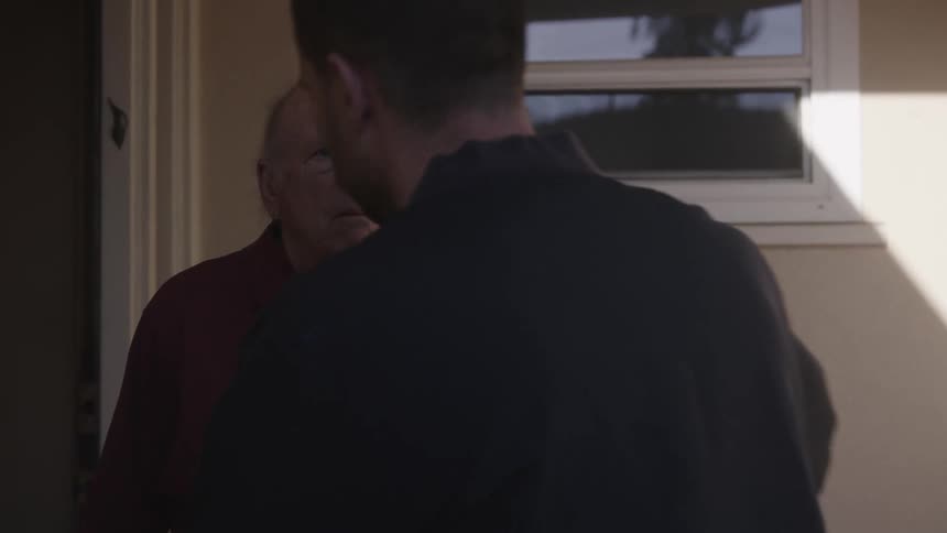 A senior man looking shocked and disappointed stares at the person approaching him for a hug