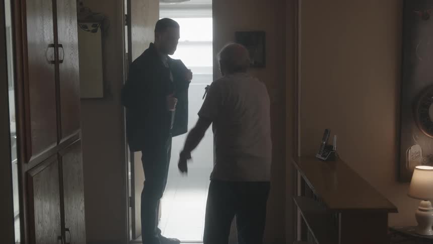 Elderly man argues with younger man and gestures with pen