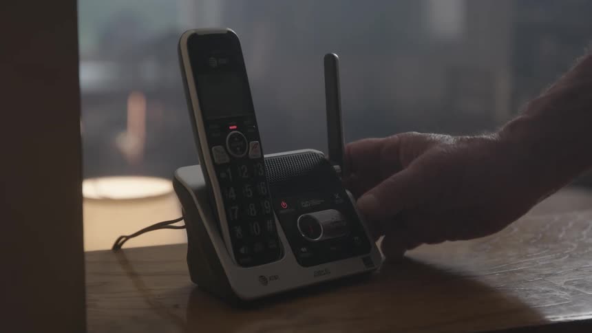 A man checks the answering machine on his cordless phone