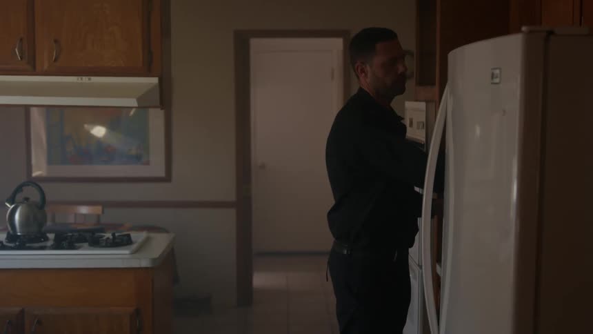 A man takes off his hat and opens the fridge in the kitchen