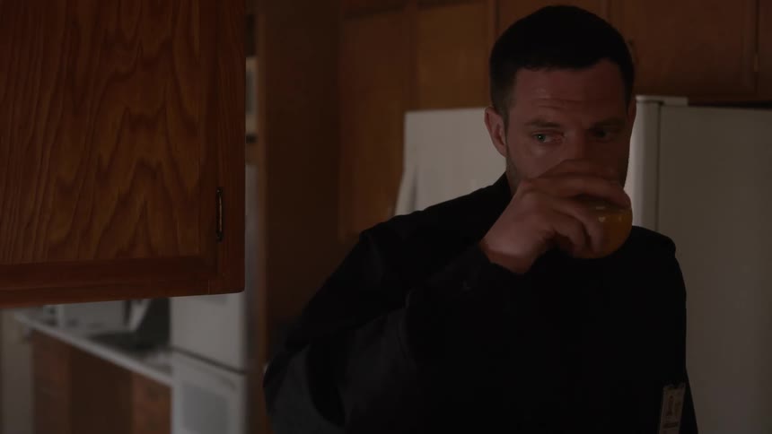 A man sips a drink after closing the fridge
