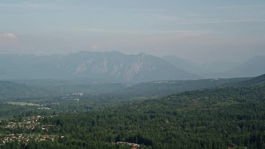  aerial footage of the Cascade Range in Washington seen from an evergreen forest with a hazy ambiance