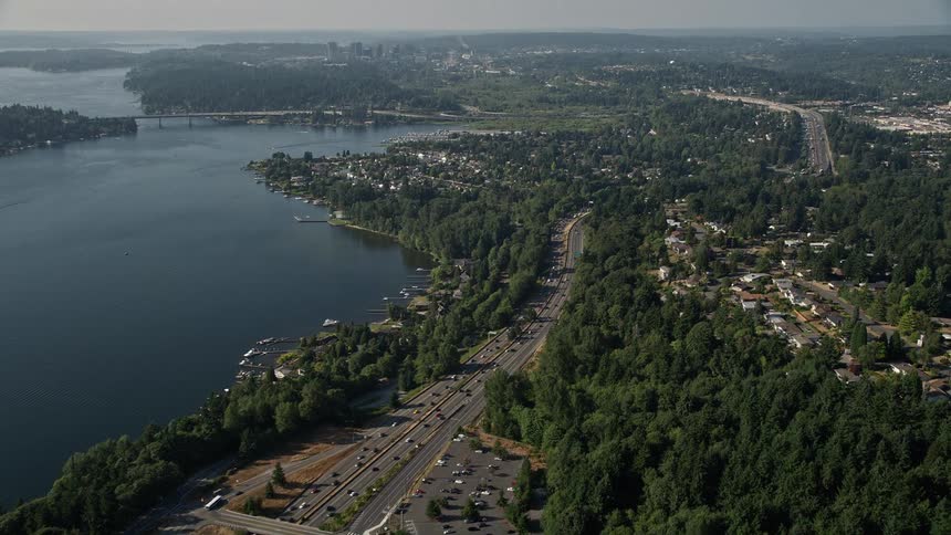 Aerial footage of traffic moving along Interstate 405 through a lakeside residential area on the shores of Lake Washington in Bellevue Washington on a sunny day