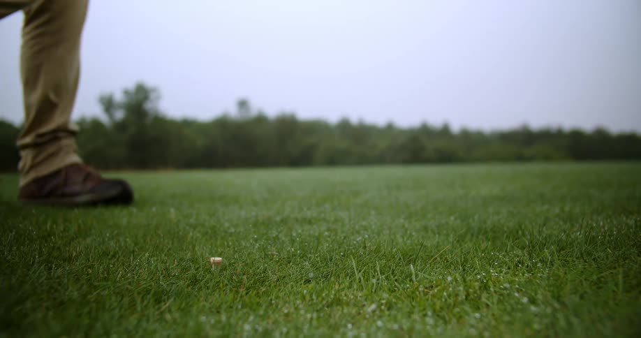 Golfer with brown shoes and pants hits ball with golf club in the golf club