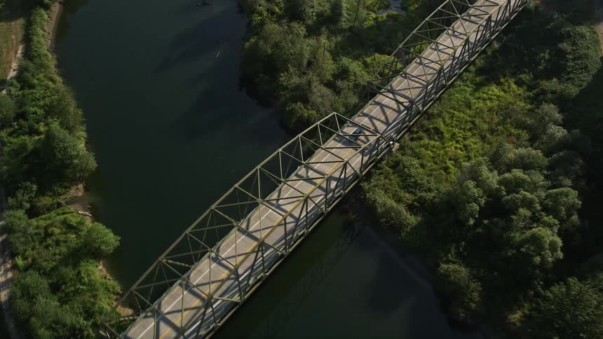 Aerial footage of vehicles traveling over a bridge on the Snoqualmie River in Carnation Washington showcasing the surrounding farmland and natural river