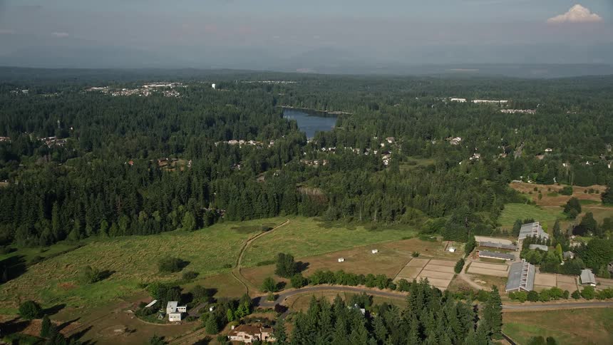 Aerial footage of lakefront homes with docks and trees approaching rural homes and Pine Lake in Sammamish Washington on a sunny day