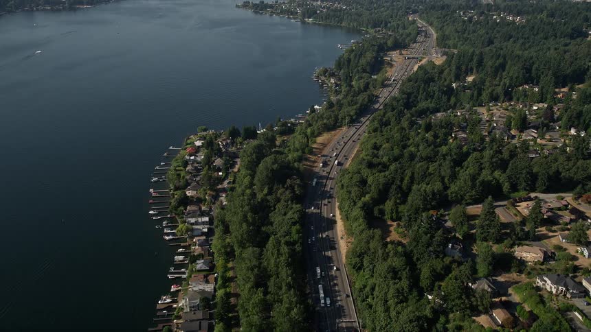 Aerial view of approaching I-405 and lakeside homes in Bellevue Washington with cars driving on the highway next to the sea