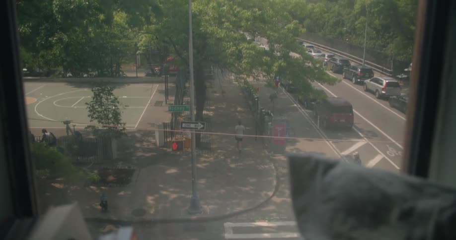A view from an apartment window of a man running in a city street