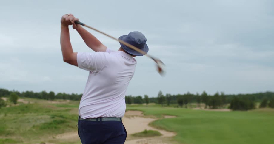 A man swings a golf club on a golf course