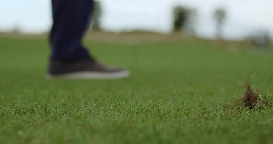 Close up of a golfer hitting a ball ripping the green grass