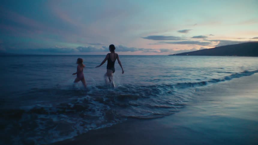 A mother and daughter running into the ocean