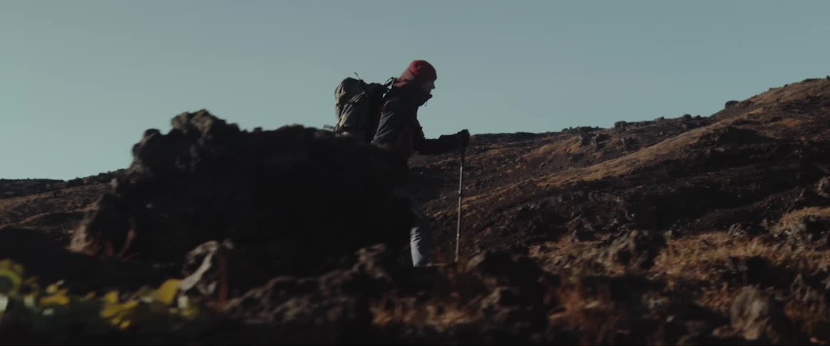 A man uses walking sticks to hike through a canyon