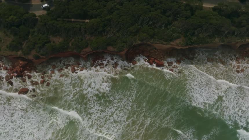Waves crash onto the shore below a cliff