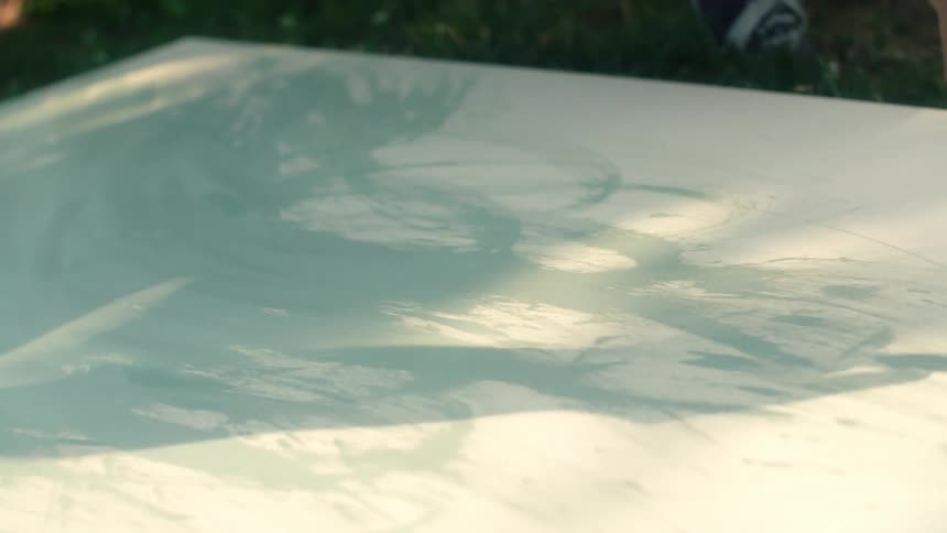 A person is painting on a canvas while sitting outdoors